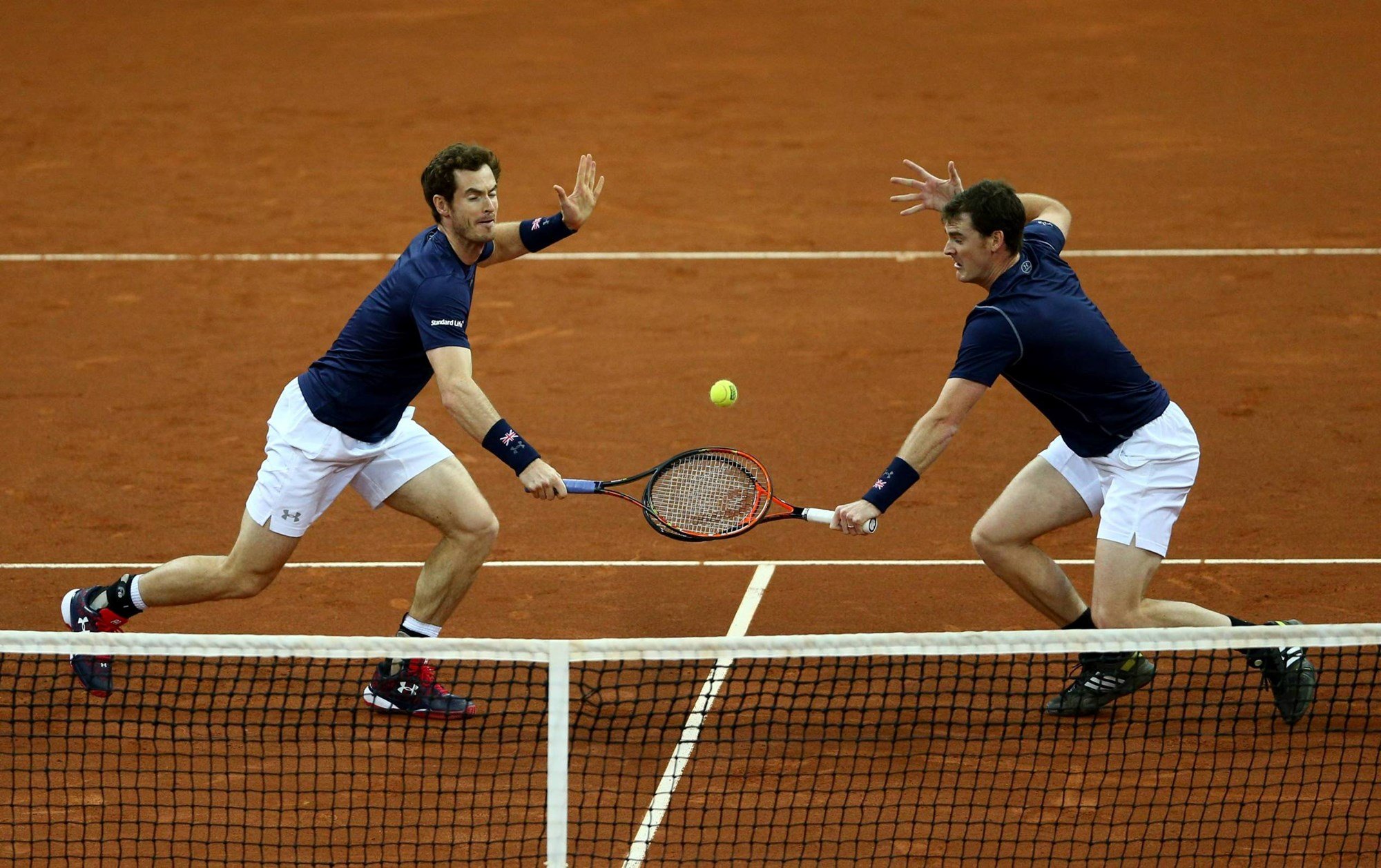 Andy Murray and Jamie Murray reach for a volley in the doubles match against David Goffin and Steve Darcis of Belgium on day two of the Davis Cup Final 2015