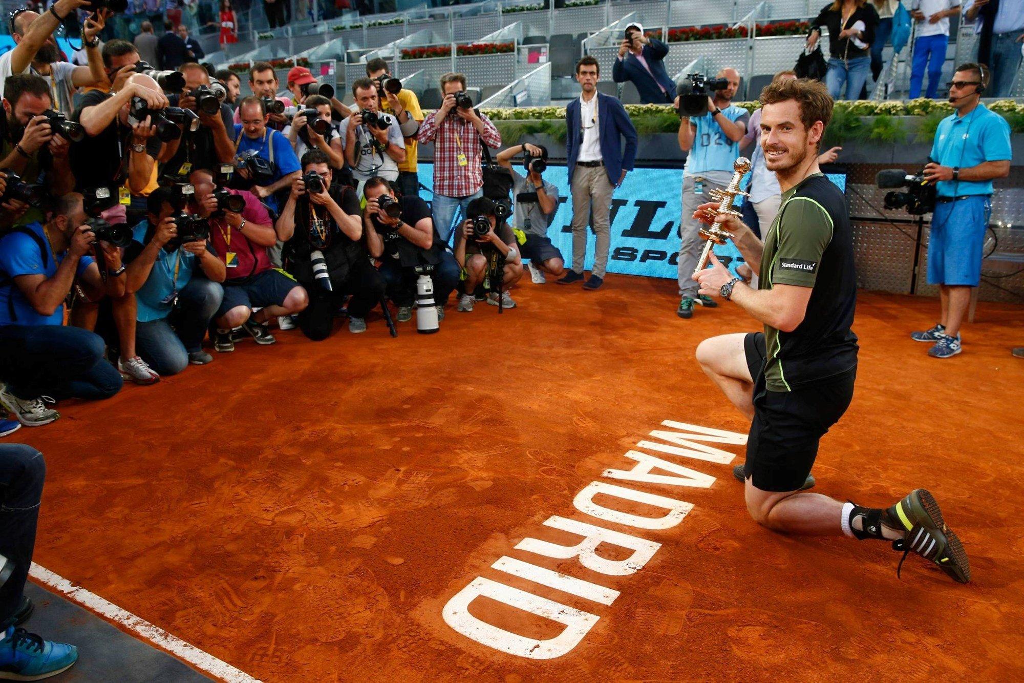 Andy Murray with the winners trophy by the court logo after his win over Rafael Nadal of Spain in the final of the 2015 Mutua Madrid Open