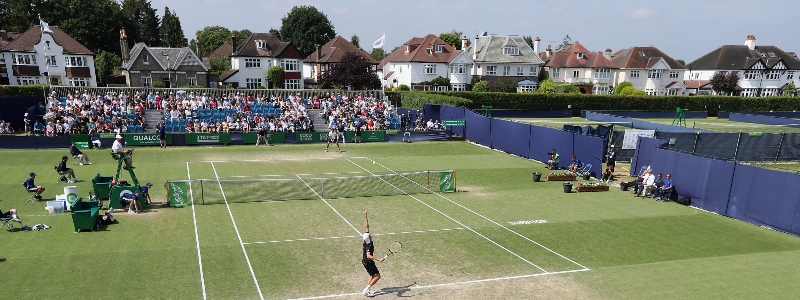 Player serving on the grass courts of Surbiton Tennis Club