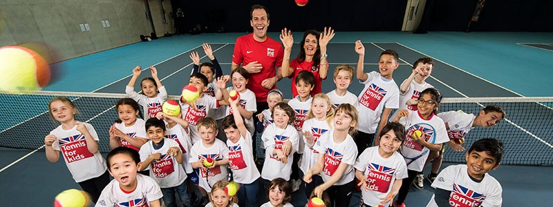 Large group of kids with tennis balls on a tennis court