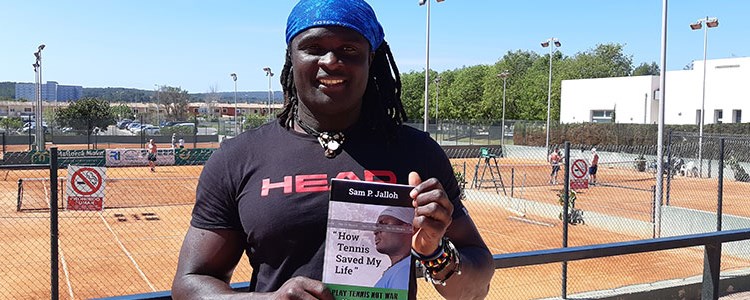 Sam Jalloh holding his book in front of tennis courts