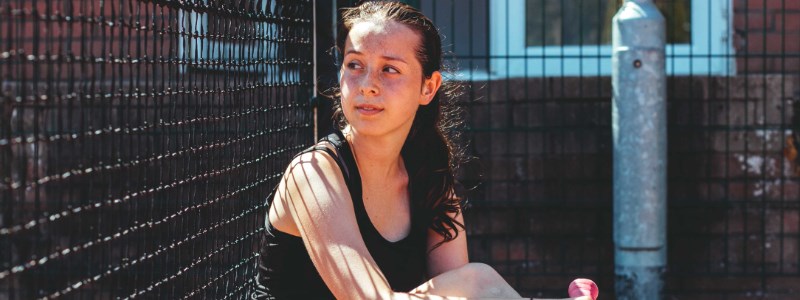 alanna sitting on the floor of the tennis court looking away