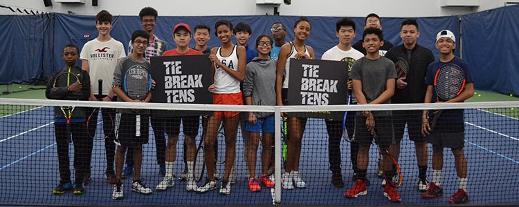 Group of junior tennis players on a court holding a 'tie break tens' sign