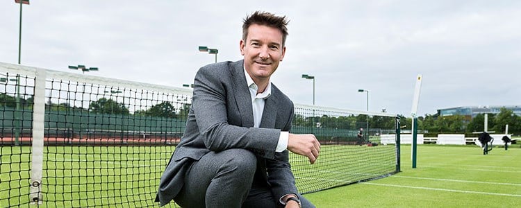 Scott Lloyd crouching down and smiling on a tennis court