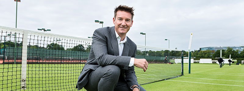 Scott Lloyd crouching down and smiling on a tennis court