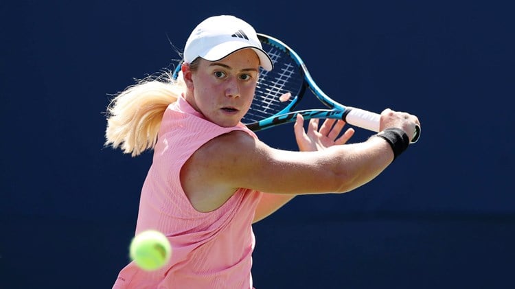 British tennis player Sonay Kartal wearing a pink top with a white Adidas hat while hitting a backhand slice at the US Open