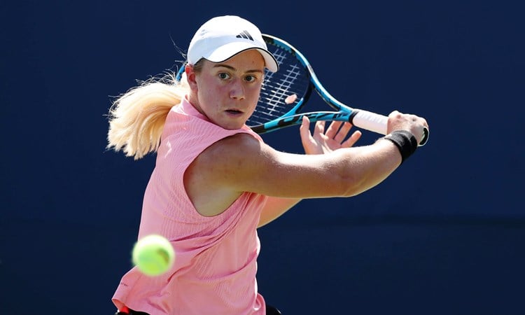 British tennis player Sonay Kartal wearing a pink top with a white Adidas hat while hitting a backhand slice at the US Open