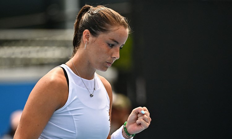 British tennis player Jodie Burrage wearing a white top and clenching her fist after winning a point in a tennis match