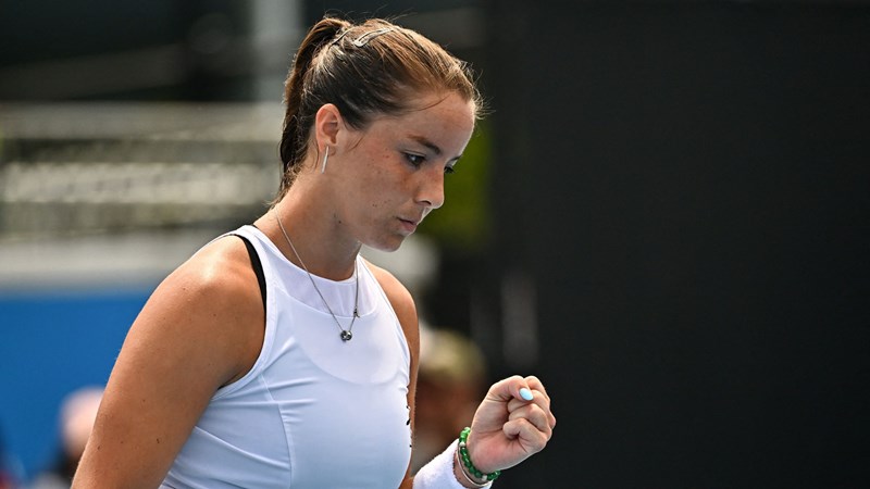 British tennis player Jodie Burrage wearing a white top and clenching her fist after winning a point in a tennis match