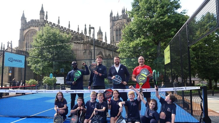 A group of young children and comedian and tv presenter Jason Manford holding padel rackets on a padel court in Manchester city centren Manford  