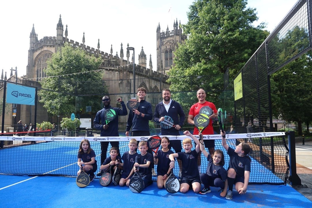 A group of young children and comedian and tv presenter Jason Manford holding padel rackets on a padel court in Manchester city centren Manford  