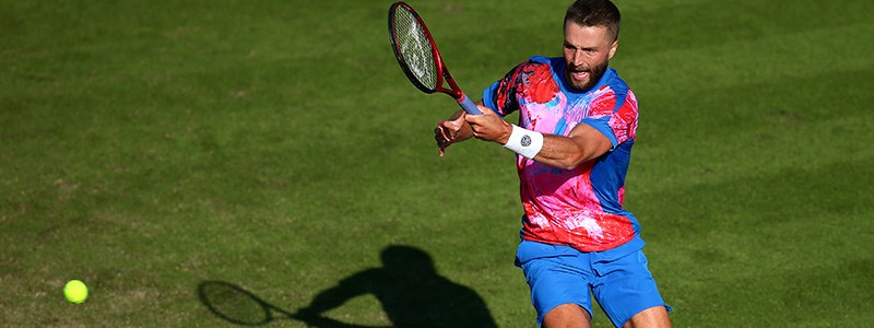 Liam Broady playing a forehanded shot on a tennis court