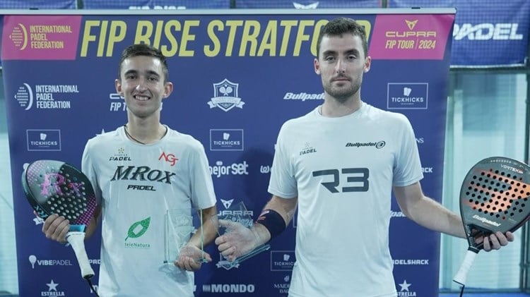 British padel player Christian Medina Murphy holding his padel bad in one hand the FIP Rise Stratford trophy in the other alongside his doubles partner at the FIP Rise event at Stratford Padel Club.