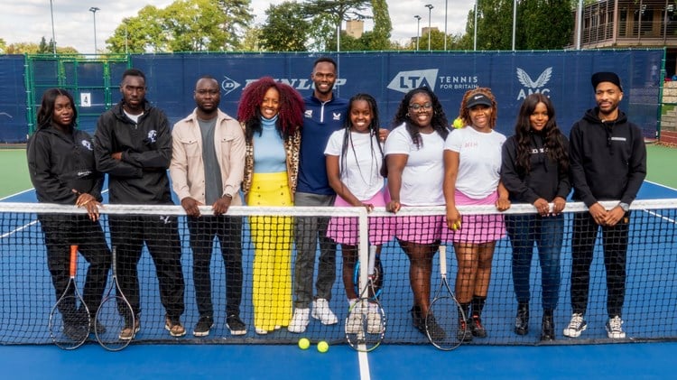 A group of people stood on a tennis court while holding the tennis net to form the Black Tennis Collective