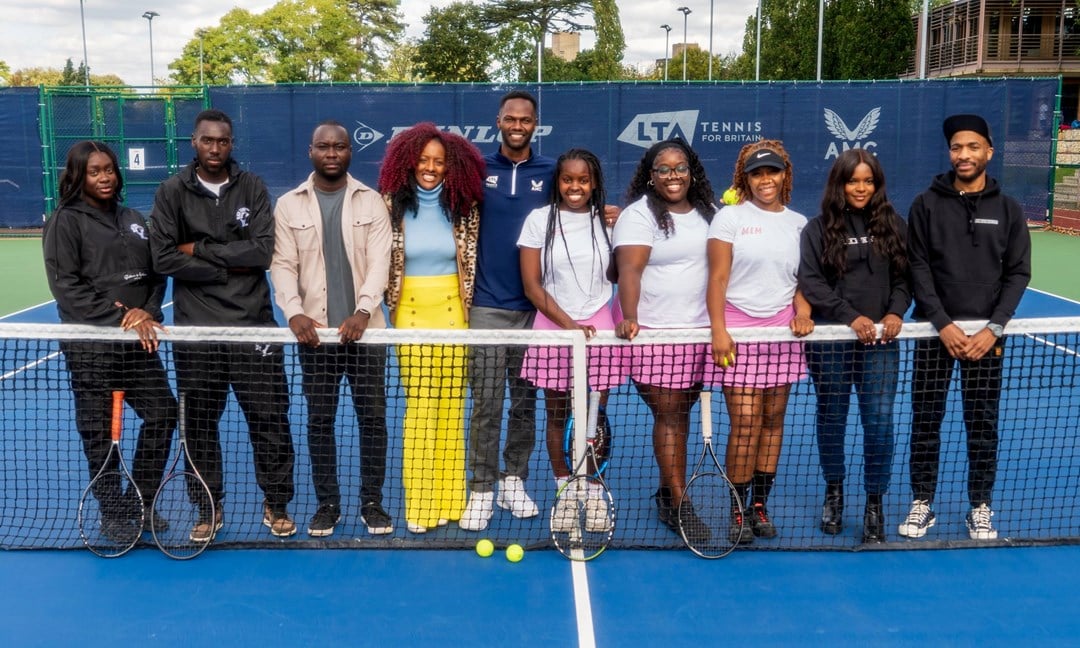 A group of people stood on a tennis court while holding the tennis net to form the Black Tennis Collective