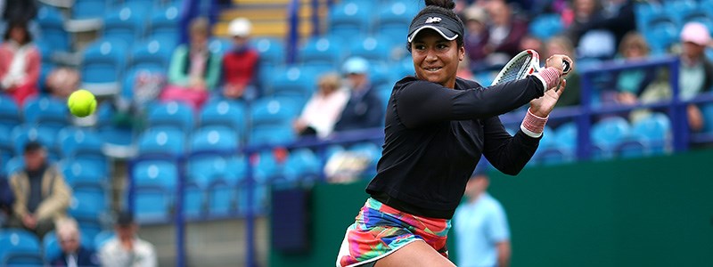 Heather Watson playing a double backhand shot in a tennis match with a crowd watching in the background