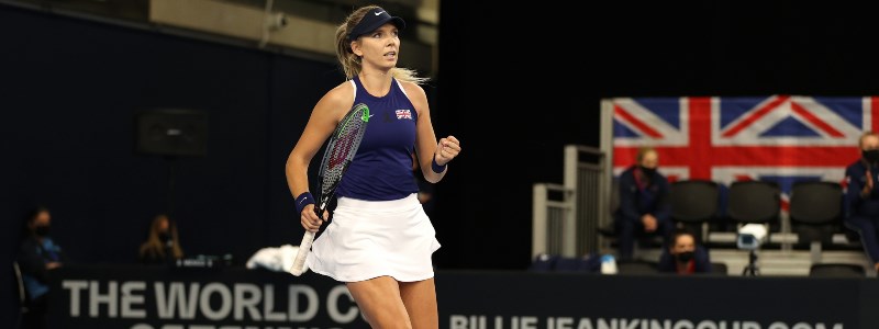 Katie Boulter celebrating on a tennis court with her tennis racket in front of an audience