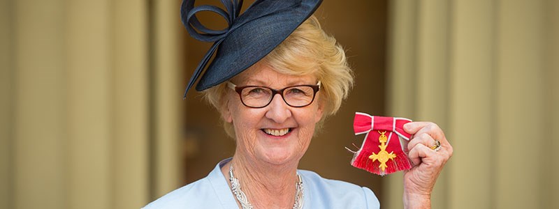 Cathie Sabin honoured with an OBE in 2016, holding it up to the camera