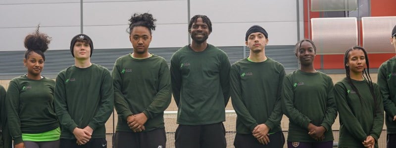 A group of people lined up side-by-side together all wearing green uniforms