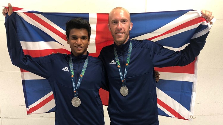 Esah Hayat and Lewis Fletcher pose behind union jack flag with their medals