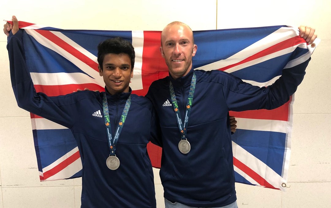 Esah Hayat and Lewis Fletcher pose behind union jack flag with their medals