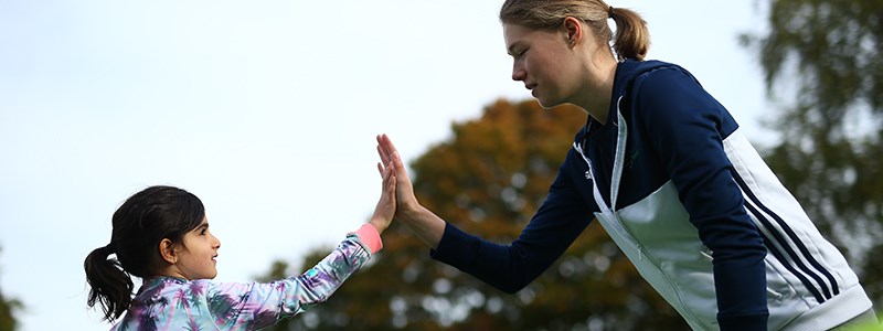 kid hi-fiving with adult coach