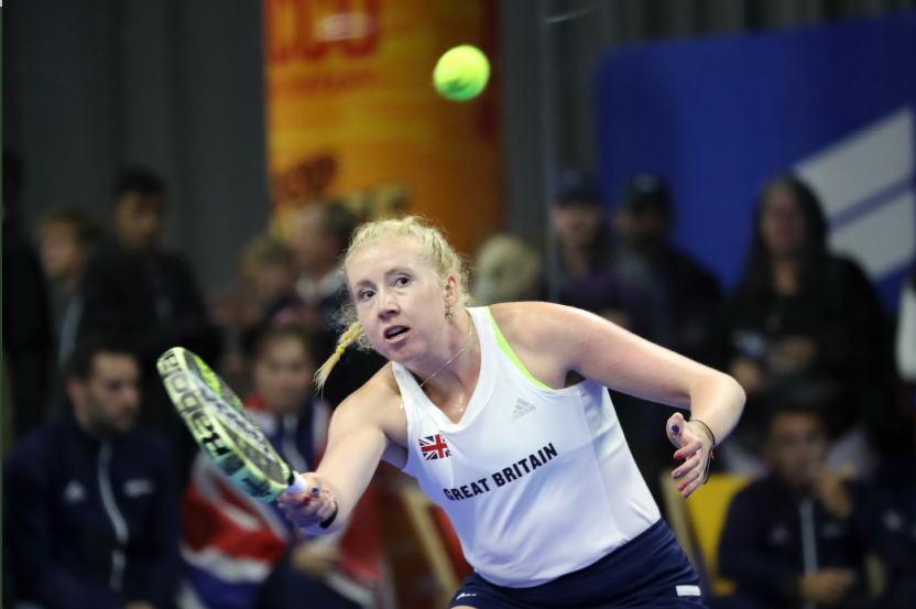 British padel player Lisa Phillips holding a padel bat while preparing to hit a ball on court