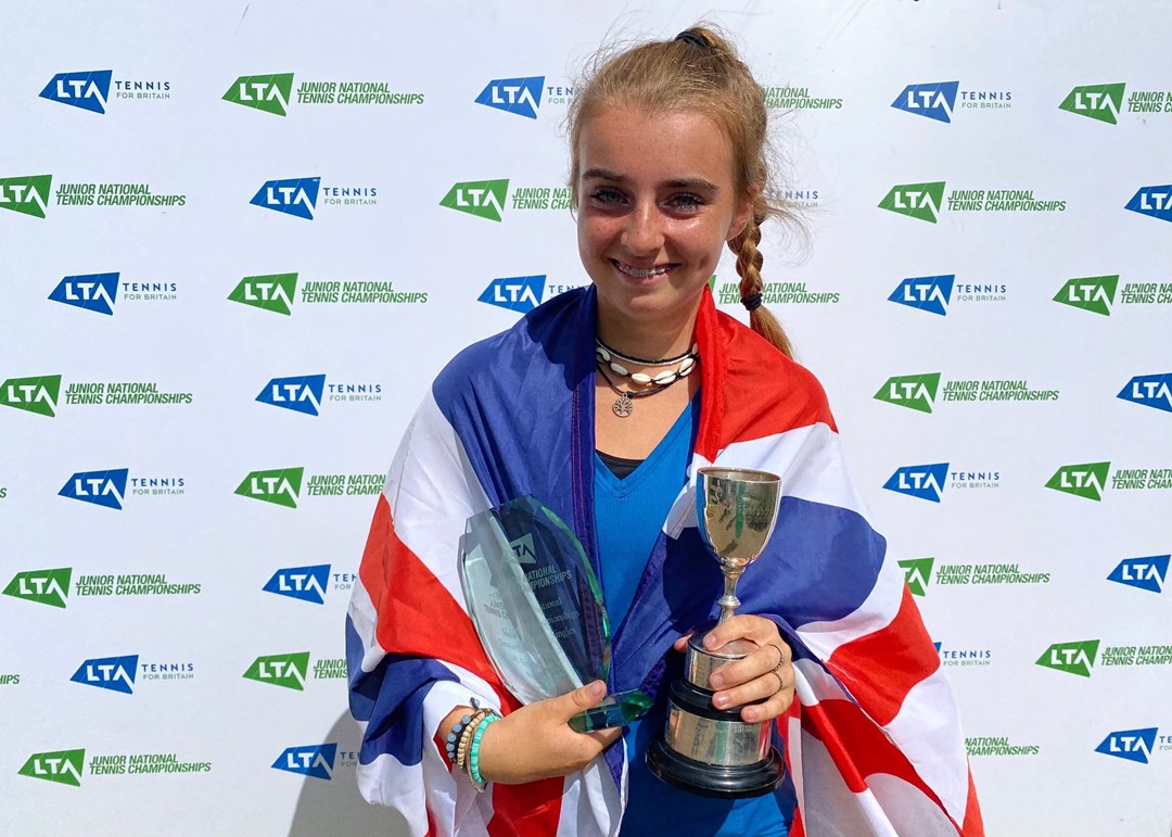 Female holding a trophy wrapped around in a flag