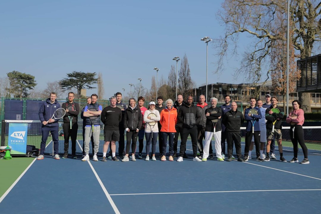 A group of people holding rackets on a tennis court