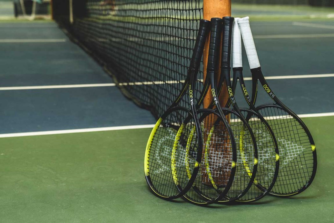 Bunch of tennis rackets resting on a pole