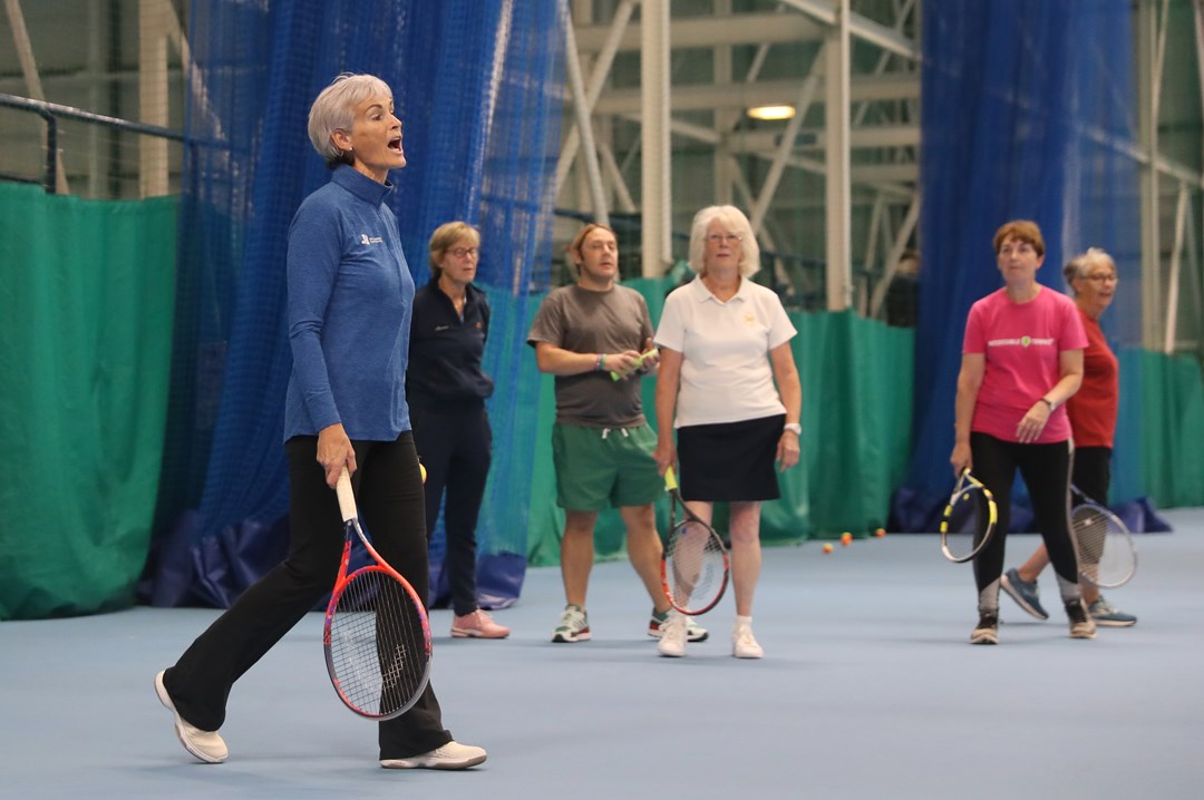 Judy Murray in sports hall speaking with teachers watching in background