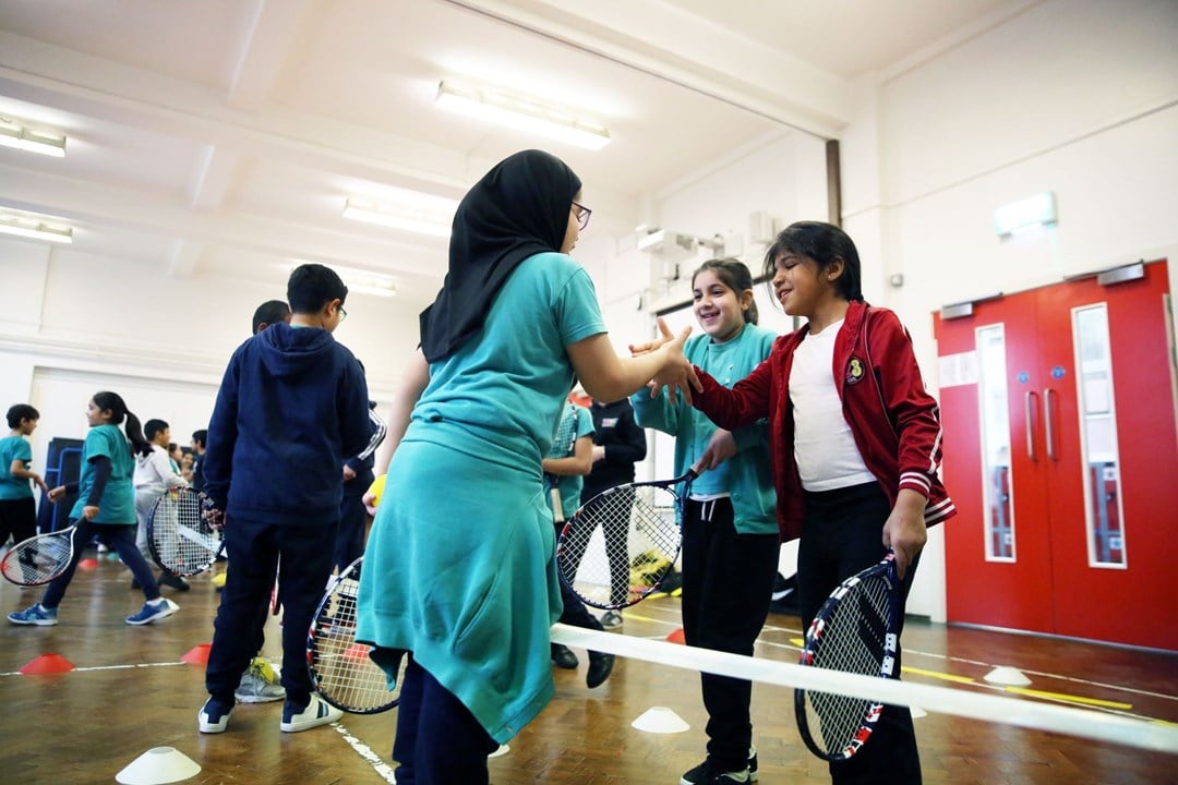 Female tennis instructor teaching a youth tennis lesson.